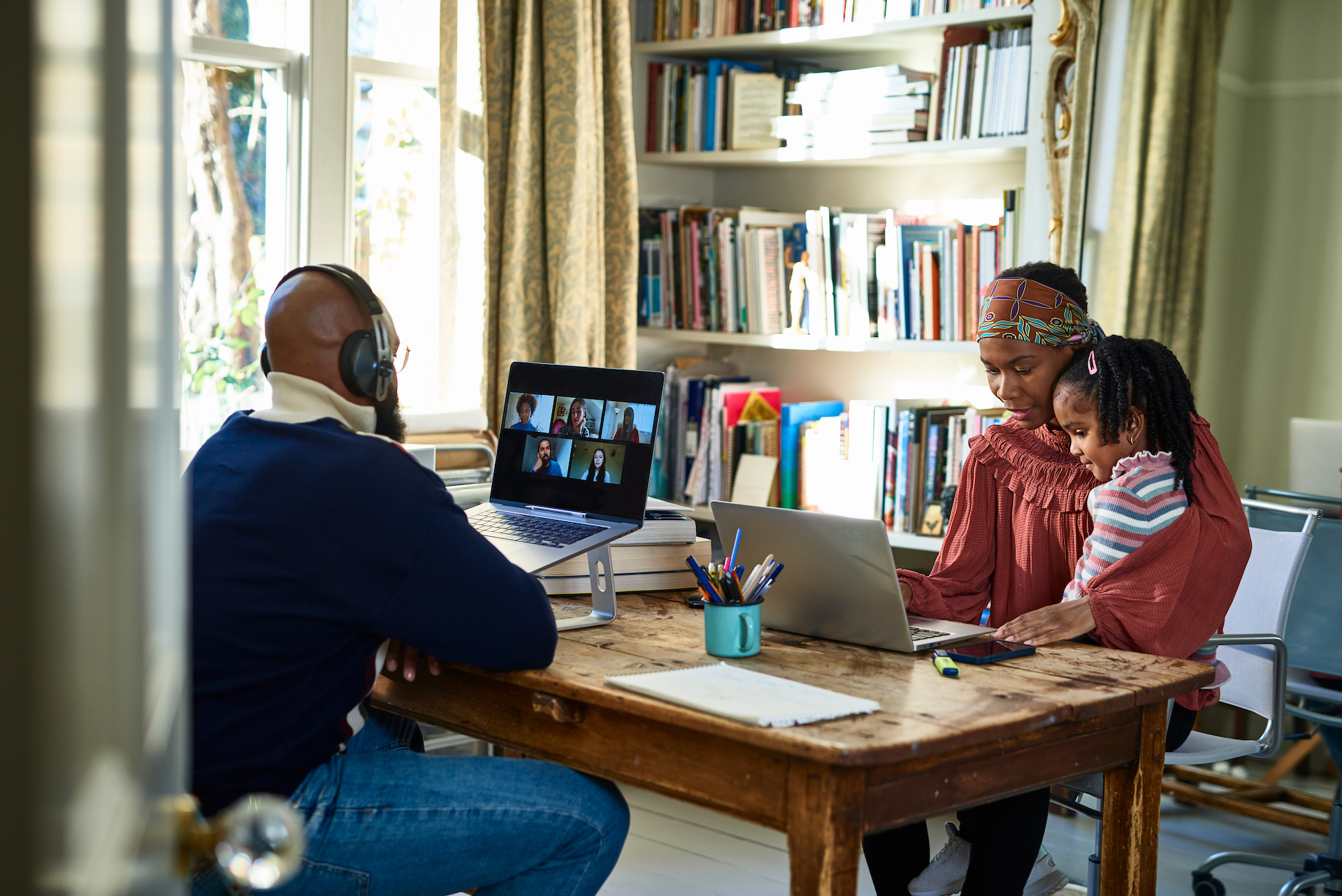 Two black parents with their young child working in home office