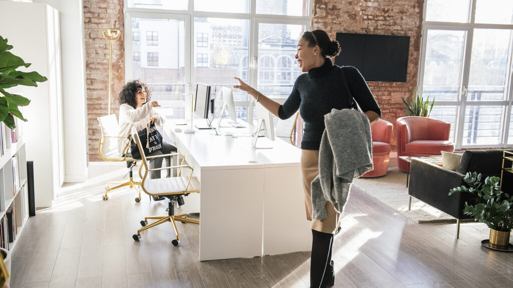 Woman waving goodbye to colleague in office