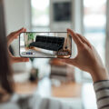 Over the shoulder view of young woman buying furnitures with augmented reality technology on smartphone