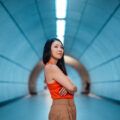 Confident young Asian woman with arms crossed, standing in modern train station