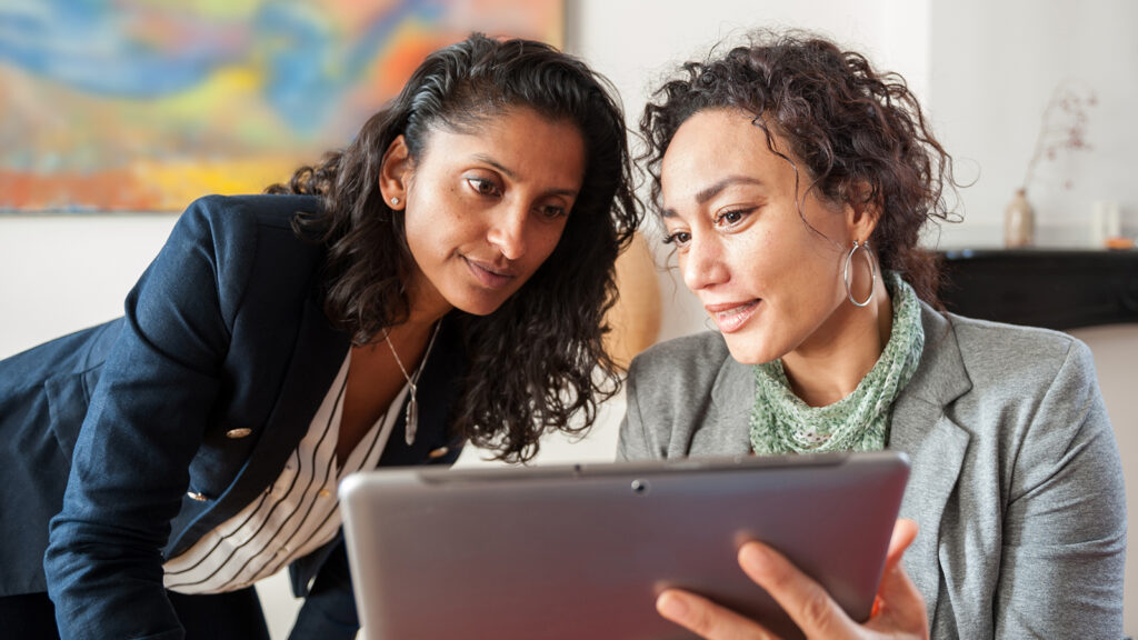 Two business women looking at a tablet computer, discussing a topic