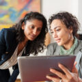 Two business women looking at a tablet computer, discussing a topic