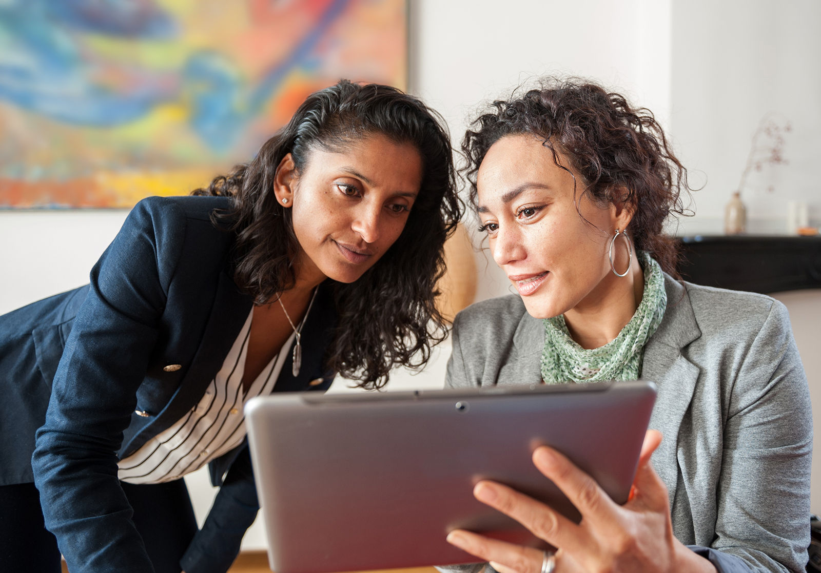 Two business women looking at a tablet computer, discussing a topic
